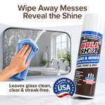 A hand wipes a bathroom mirror with a blue cloth, removing streaks. Beside the mirror is Bull Shot Glass & Mirror Cleaner, offering a streak-free shine. Text highlights it's made in the USA and works as an effective glass cleaner.